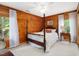 Comfortable bedroom featuring wood paneling, natural light, and a classic four-poster bed at 3009 Pleasant Hill Church Rd, Siler City, NC 27344