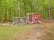 Red chicken coop with fenced area in a wooded backyard at 3009 Pleasant Hill Church Rd, Siler City, NC 27344