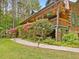 Flag adorns a log cabin with a stone pathway surrounded by lush greenery and flowering bushes at 3009 Pleasant Hill Church Rd, Siler City, NC 27344