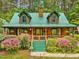 Charming log home boasts a green metal roof, inviting porch, and beautiful flowering bushes at 3009 Pleasant Hill Church Rd, Siler City, NC 27344