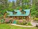 Charming log home features a green metal roof, landscaped front yard, and inviting front porch at 3009 Pleasant Hill Church Rd, Siler City, NC 27344