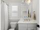 Bright bathroom featuring a shower with a white curtain and hexagon-patterned tile, plus a white vanity with brass fixtures at 3138 Curling Creek Dr, Apex, NC 27502