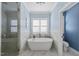 Bright bathroom with free-standing tub, glass shower, and large window at 3138 Curling Creek Dr, Apex, NC 27502