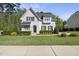 Charming white brick two-story home featuring a landscaped front yard with mature trees and dark shutters at 3138 Curling Creek Dr, Apex, NC 27502
