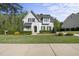 Charming two-story home with a manicured lawn, lush landscaping, and white brick at 3138 Curling Creek Dr, Apex, NC 27502