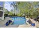 Inviting in-ground pool with basketball hoop, stone patio, and landscaped seating area in private backyard at 3138 Curling Creek Dr, Apex, NC 27502
