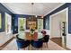 Elegant dining room features dark blue walls, a round wood table, and modern light fixture at 3312 Rock Creek Dr, Raleigh, NC 27609