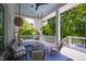 Covered porch with comfortable seating, including a daybed swing and wicker chairs, overlooking a lush backyard at 3312 Rock Creek Dr, Raleigh, NC 27609