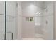 Elegant walk-in shower featuring light tile, a built-in niche, and glass doors at 3312 Rock Creek Dr, Raleigh, NC 27609