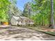 Cozy single-story house with covered porch, set on a gravel driveway, surrounded by lush trees at 3607 Springhollow Ct, Efland, NC 27243