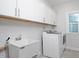 Bright laundry room with white cabinets, stainless steel washer and dryer, and utility sink at 361 Natsam Woods Way, Wake Forest, NC 27587
