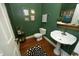 Powder room featuring green walls, a pedestal sink, gold accents, and unique artwork at 4101 John S Raboteau Wynd, Raleigh, NC 27612