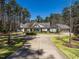 Expansive gray home with manicured lawn, circular driveway, and attached three-car garage against a backdrop of mature trees at 464 Rosemont Dr, Durham, NC 27713