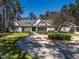 Stately gray home featuring manicured lawn, circular driveway, and lush landscaping against a backdrop of mature trees at 464 Rosemont Dr, Durham, NC 27713