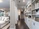 Hallway featuring dark hardwood floors, white columns, and built-in bookshelves, leading to a living room and staircase at 464 Rosemont Dr, Durham, NC 27713