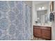 Bathroom featuring wood cabinets, decorative mirror, and a patterned shower curtain at 504 Applecross Dr, Mebane, NC 27302