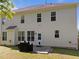 Home's rear exterior features a patio and grill with green lawn and upper and lower windows under a blue sky at 5240 Holly Ridge Farm Rd, Raleigh, NC 27616