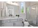 Modern bathroom with gray cabinets, large mirror, marble countertops, and a glass shower with bench at 5803 Vintage Oak Ln, Raleigh, NC 27613