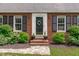 Inviting front entrance with a brick facade, black shutters, and well-manicured landscaping at 615 Beaver Creek Rd, Apex, NC 27502