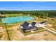 Stunning aerial view of a white farmhouse with a covered porch, long driveway, and private pond surrounded by lush greenery at 6185 Nc-50, Benson, NC 27504
