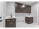 Laundry room features dark wood cabinets, marble-patterned floors, sink and hanging rod at 6185 Nc-50, Benson, NC 27504