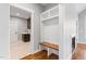 Bright mudroom featuring custom built-in bench and shelving, hardwood floors, and adjacent laundry room at 6185 Nc-50, Benson, NC 27504