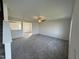 Open-concept living room with neutral carpeting, ceiling fan, and view into the adjacent kitchen at 63 Coharie Dr, Lillington, NC 27546