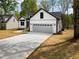 Side view of a modern home showcasing a gray two-car garage and complementary landscaping at 648 Shawnee Dr, Louisburg, NC 27549