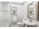 All-white bathroom features mosaic tile flooring, a built-in shelf, and tub with shower at 804 Old Mill Rd, Chapel Hill, NC 27514