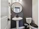 Contemporary half bathroom features a round mirror, pedestal sink, and sleek fixtures at 805 Winter Meadow Dr, Wake Forest, NC 27587