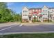 A vibrant townhome with a mix of beige, red, and gray exterior, complemented by lush green trees and grass at 805 Winter Meadow Dr, Wake Forest, NC 27587