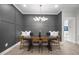 This dining room boasts elegant paneling and a contemporary chandelier over a wooden table at 8237 Baronleigh Ln, Wake Forest, NC 27587