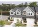 View of townhomes with stone accents, attached garages, and lush landscaping for curb appeal at 8426 Garnet Rose Ln, Raleigh, NC 27615