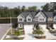 View of townhomes with stone accents, attached garages, and lush landscaping for curb appeal at 8426 Garnet Rose Ln, Raleigh, NC 27615