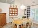 Bright dining room featuring a wooden table and chairs, wood floors, a chandelier, and an appealing blue and white curtain accent at 8712 Attingham Dr, Raleigh, NC 27615