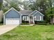 Charming single-story home featuring a blue exterior, white trim, a well-manicured lawn, and an attached two-car garage at 8712 Attingham Dr, Raleigh, NC 27615
