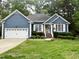 Charming single-story home featuring a blue exterior, white trim, a well-manicured lawn, and an attached two-car garage at 8712 Attingham Dr, Raleigh, NC 27615