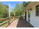 Lovely wooden deck with railing overlooks a peaceful wooded property and the home's exterior at 901D Gibson Rd, Mebane, NC 27302