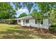 Exterior view of home's front and carport amidst a green yard, tree-lined lawn and shade at 901D Gibson Rd, Mebane, NC 27302