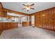Open-concept living area with a view into the kitchen, wood paneling, and cozy neutral carpet at 901D Gibson Rd, Mebane, NC 27302
