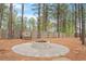 Backyard with fire pit, circular stone patio, wooden bench, and natural setting with mature trees and a wooden fence at 101 Jewell Farm Lane, Holly Springs, NC 27540