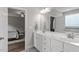 Bright bathroom featuring a double sink vanity with white cabinets and view into the bedroom at 101 Jewell Farm Lane, Holly Springs, NC 27540