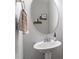 Cozy half-bath with round mirror, pedestal sink, and decorative accents at 101 Jewell Farm Lane, Holly Springs, NC 27540