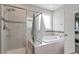 Beautiful bathroom with a glass-enclosed shower, soaker tub, and neutral tile at 101 Jewell Farm Lane, Holly Springs, NC 27540