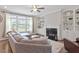Cozy living room with a fireplace, built-in bookshelves, large windows, and comfortable seating, creating a relaxing ambiance at 101 Jewell Farm Lane, Holly Springs, NC 27540