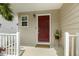 Welcoming front porch with a charming red door, white railing, and a decorative fern at 104 Caley Rd, Apex, NC 27502