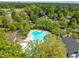 Aerial view of sparkling blue community pool surrounded by mature trees with tennis courts and lake beyond at 105 Breakers Pl, Cary, NC 27511