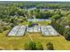 Aerial view of well maintained community tennis courts with lake in the background surrounded by mature landscaping and trees at 105 Breakers Pl, Cary, NC 27511