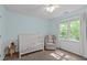 Cozy bedroom with a crib, rocking chair, and large window letting in natural light at 107 Candy Apple Ct, Cary, NC 27513