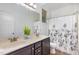Bathroom featuring a double vanity sink with dark cabinets, decorative mirror, and floral shower curtain at 1209 Shasta Daisy Dr, Wake Forest, NC 27587